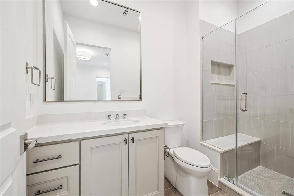 En-suite bathroom for final second-floor bathroom features a class-enclosed freestanding shower lined with Maniscalco Contour glossy tiles. Quartz counters and additional counter and storage space complete this bathroom.