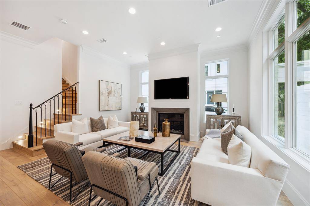 The expansive living room features an elegant 42” fireplace with herringbone tile design, wrought iron stairway detail, LED integrated recessed lighting and Pella Lifestyle windows.