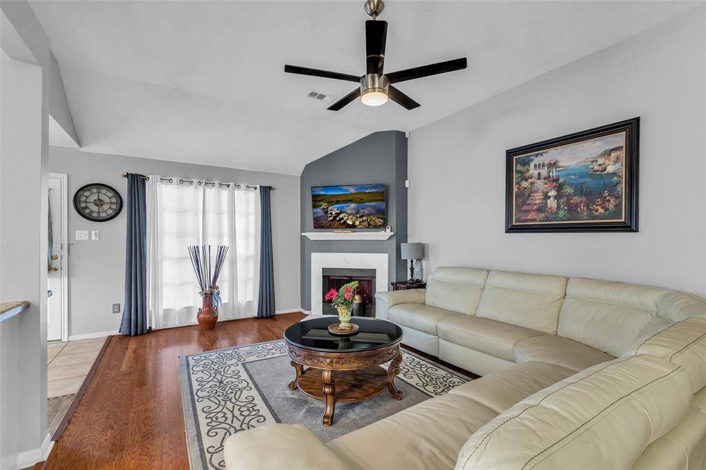 Amazing living room with a beautiful fireplace and a large window, wood flooring and ceiling fan.