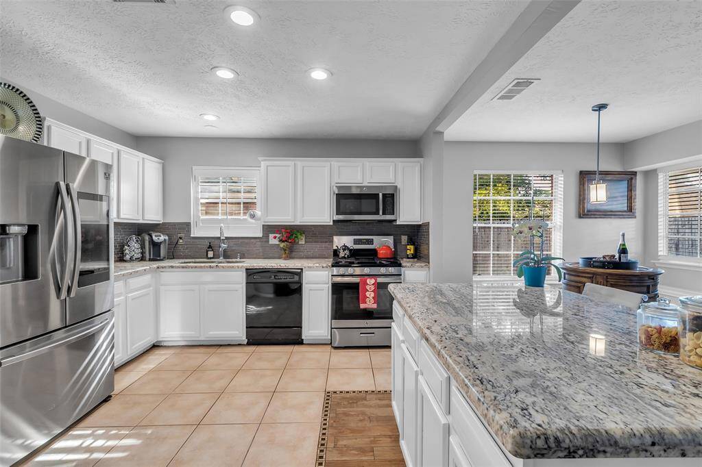 Impressive kitchen with a big island, ton of cabinets, stainless steel appliances and counter space.