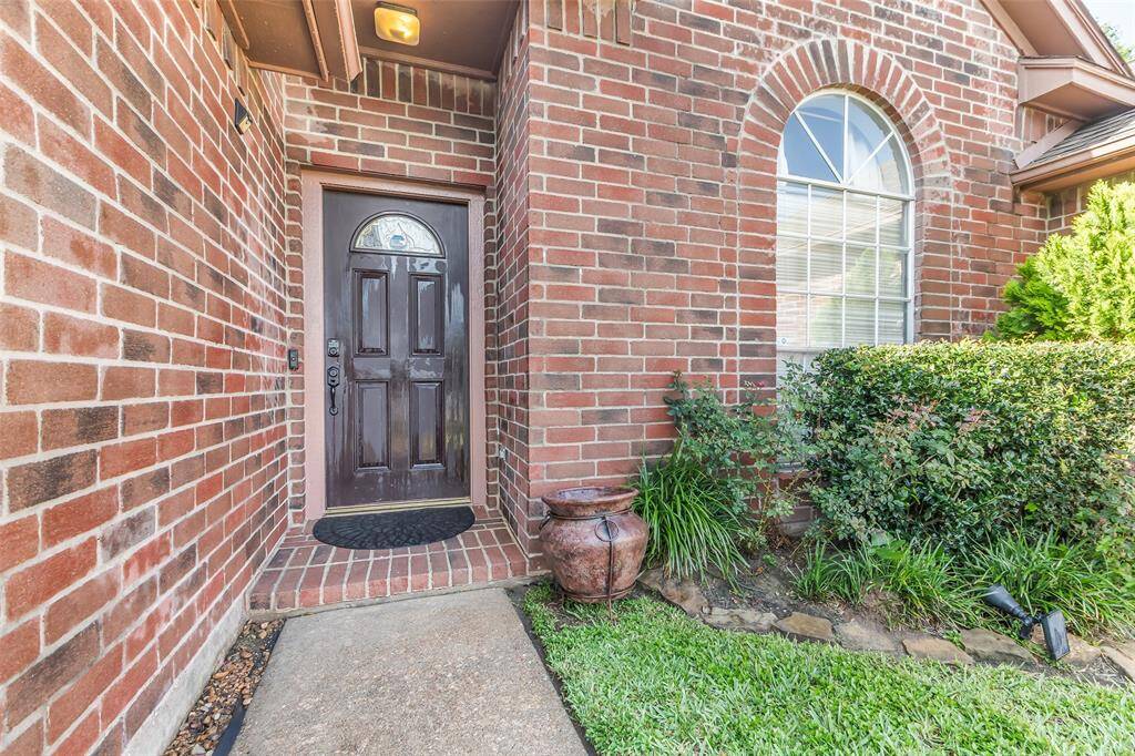 Inviting front entrance with all bricks and lush landscaping.