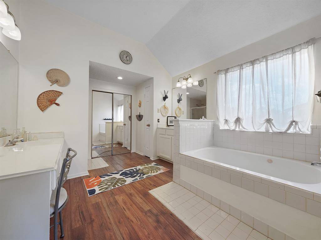 Primary bathroom features a soaking tub, walk-in shower with glass enclosure, and dual vanities.