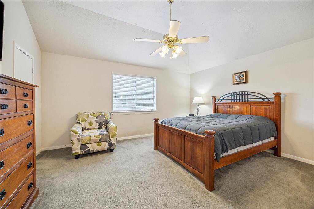 This spacious primary bedroom features a vaulted ceiling, a large window providing ample natural light.