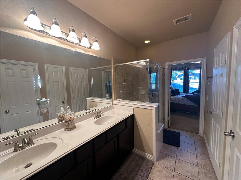 This additional view of the primary bath showcases the spacious walk-in shower with tile surround and double sinks.