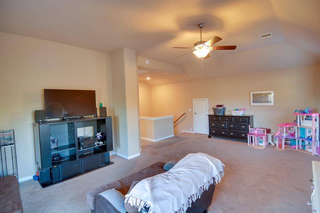 Additional view of your spacious game room with plush carpet flooring, and dark stained ceiling fan with lighting.