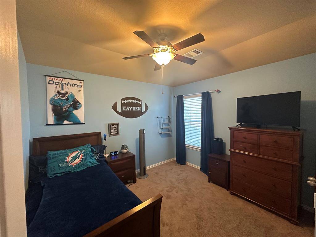 Secondary bedroom features plush carpet flooring, custom paint, modern ceiling fan with lighting and large window with natural light.