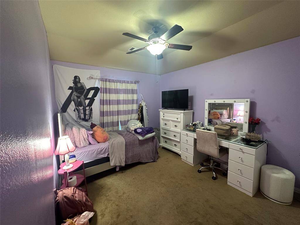 Secondary bedroom features plush carpet flooring, high ceilings, modern ceiling fan with lighting, custom paint and space for seating area.