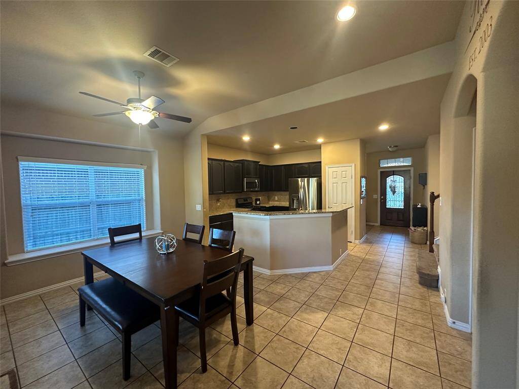 This stunning dining area features soaring high ceilings, recessed lighting and tile flooring, creating an open and airy atmosphere. The expansive layout offers ample room for personalization, while the sleek, modern tile flooring adds a touch of elegance. Perfect for both relaxing and entertaining, this room seamlessly connects to the outdoor covered patio, enhancing the flow of indoor-outdoor living.