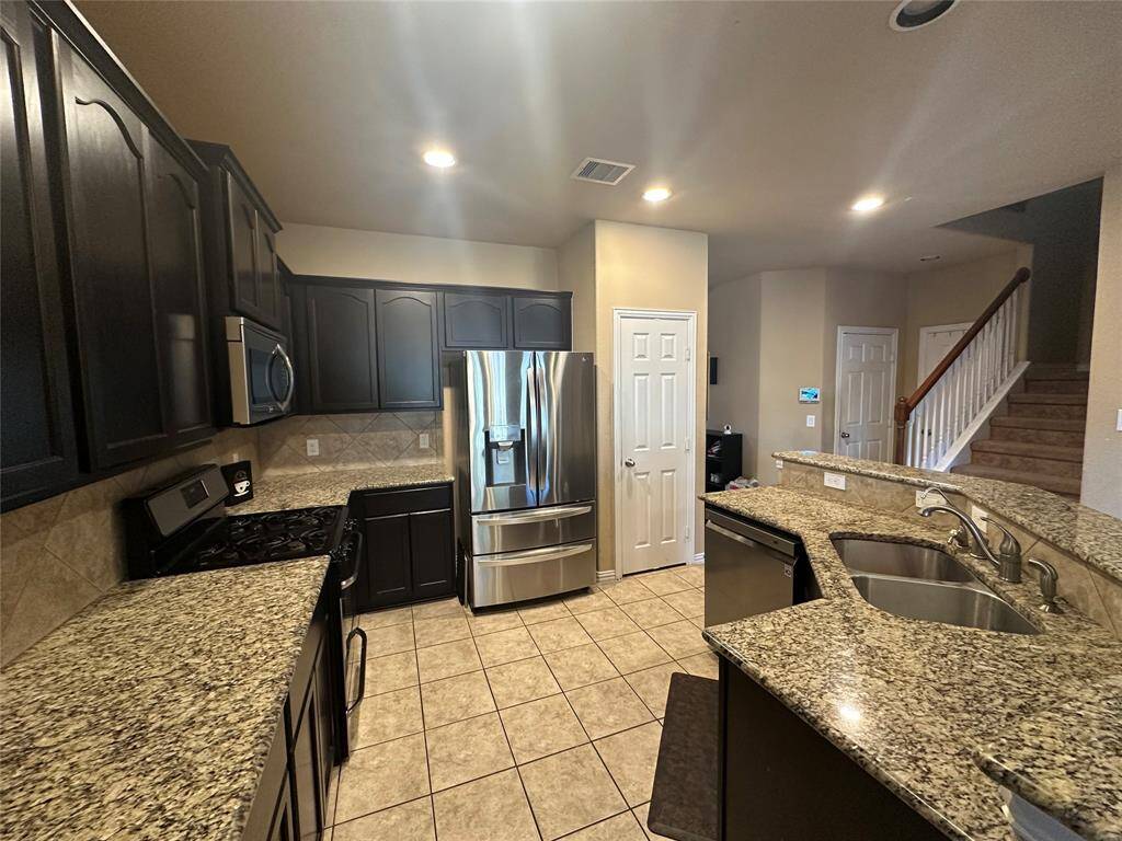 This kitchen is by far any chef's dream! This spacious kitchen features tile flooring, high ceilings, dark stained cabinets, Granite countertops, Stainless steel appliances, modern tile backsplash, recessed lighting, extended counter space, and space for breakfast bar.