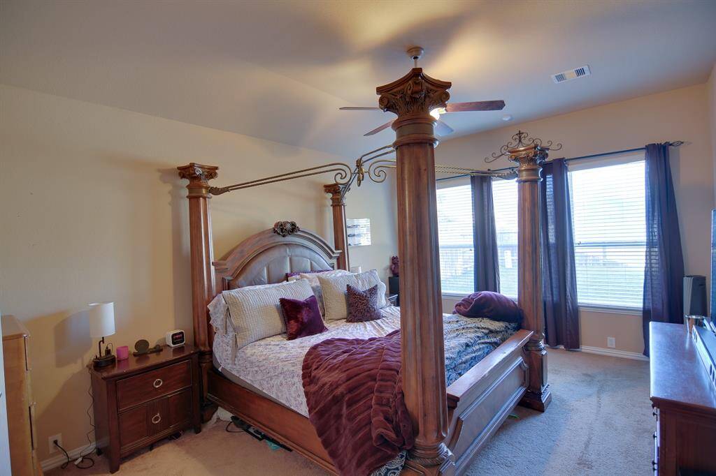 What a wonderful place to come home to, this stunning primary suite greets you with carpet flooring, a warm neutral paint, high ceiling, dark stained ceiling fan with lighting, lovely large windows allowing in natural light brightening up this spacious primary bedroom.
