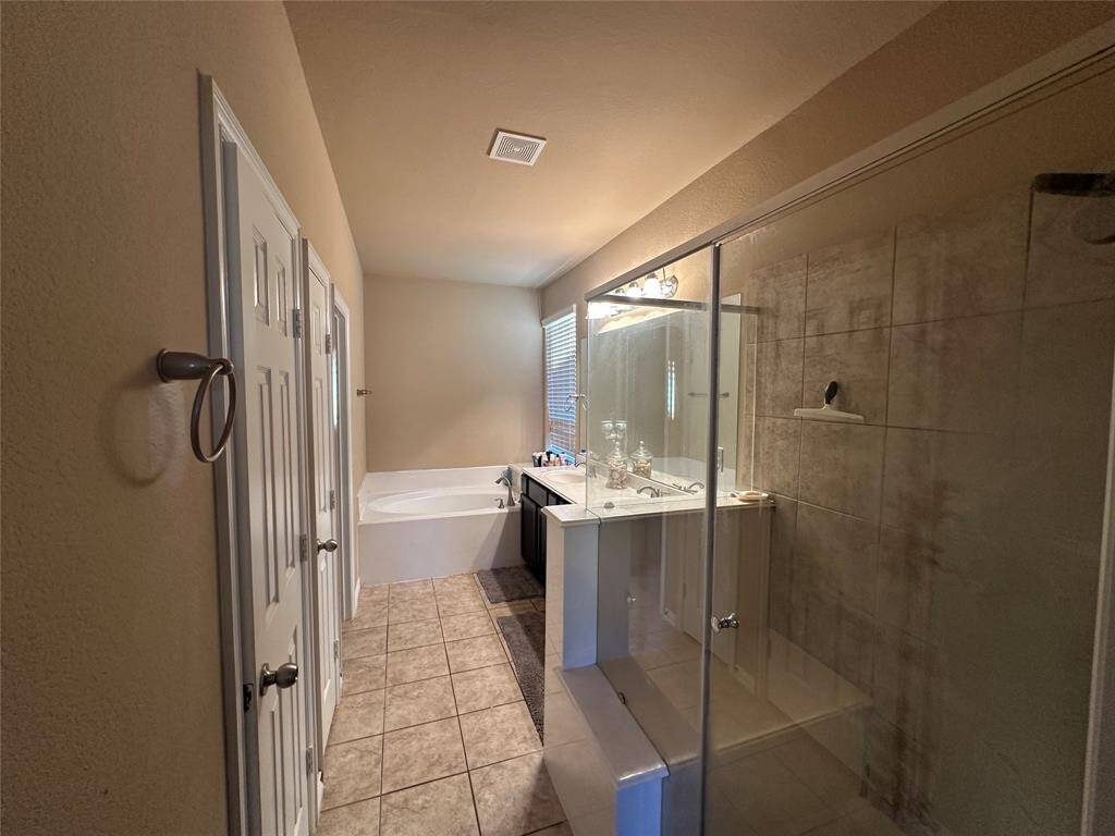 This primary bathroom is definitely move-in ready! Featuring a spa like oversized walk-in shower with tile surround, separate garden spa like tub for soaking after a long day, dark stained cabinets with light countertops, spacious walk-in closet, high ceilings, neutral paint, sleek and modern finishes.