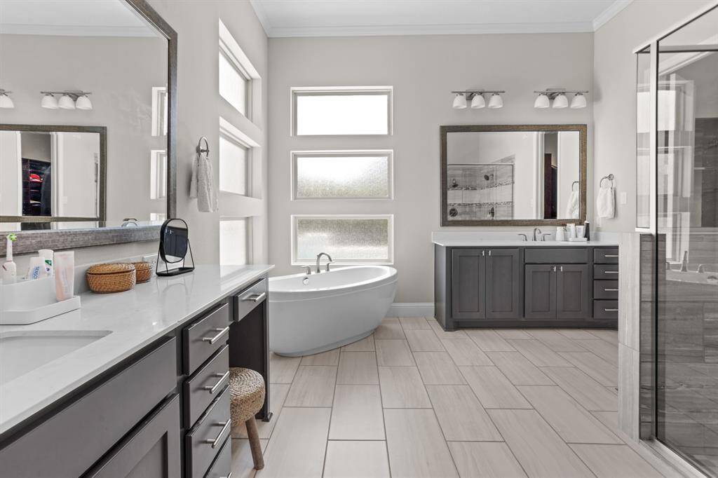 Huge primary bathroom features two sinks and separate tub and shower.