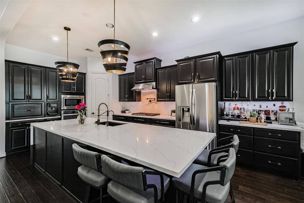Completely remodeled kitchen with stunning light fixtures and matte black and gold accents.