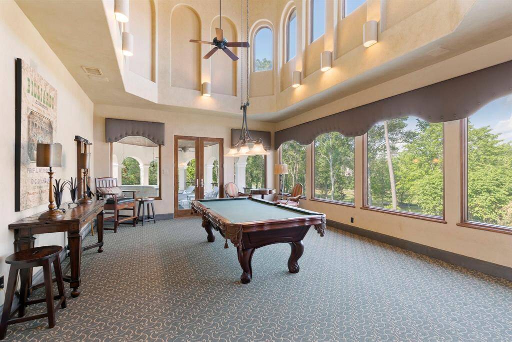 The game room is wrapped in the home's soaring signature window views and opens out to a large balcony.