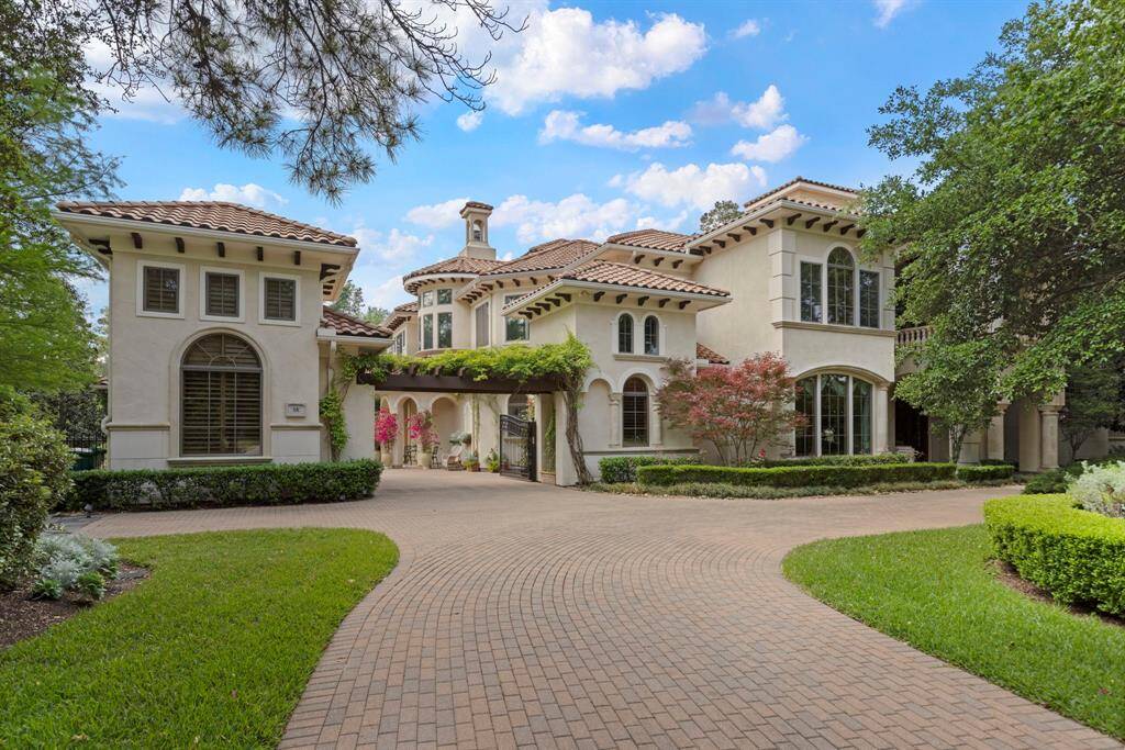 A brick paver circular driveway offers a grand welcome with vibrant gardens and meticulously designed landscape.