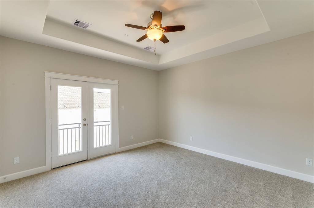 PRIMARY BEDROOM FEATURES TRAY CEILING, TASTEFUL GRAY PAINT, DOUBLE FRENCH DOORS WITH A JULIET STYLE BALCONY