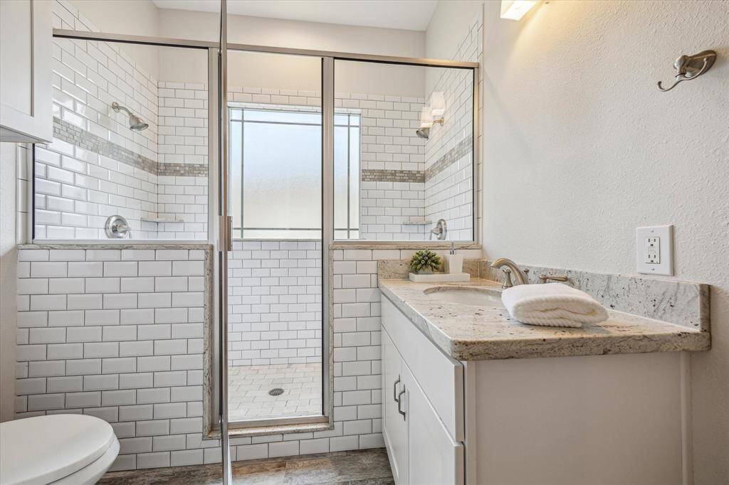 Guest bathroom located between the secondary bedrooms, featuring a sleek double shower with glass door and classic subway tile