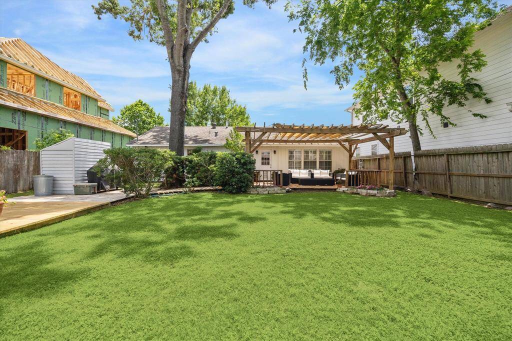 A deep backyard framed by tall trees and lush grass sets the stage for relaxing weekends and lively gatherings. The extended deck and pergola-covered lounge space invite shaded outdoor living, while privacy fencing and mature landscaping enhance the sense of seclusion.