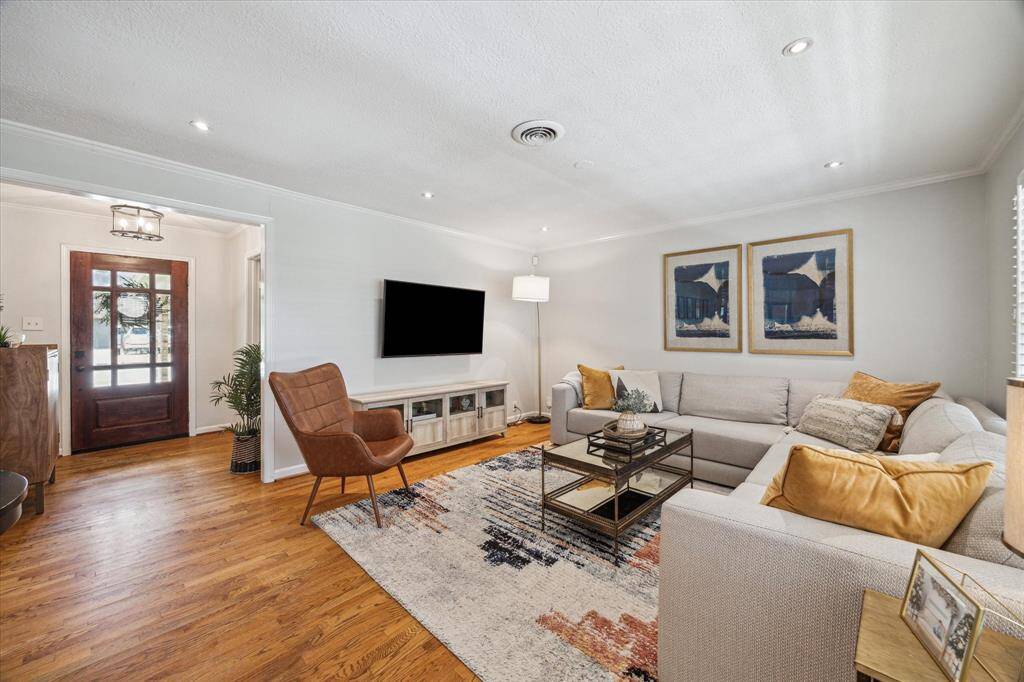 Spacious living room sits just off the front entry, featuring hardwood floors, crown molding, and recessed lighting. Large windows bring in natural light, while the layout offers plenty of room for gathering and relaxing.