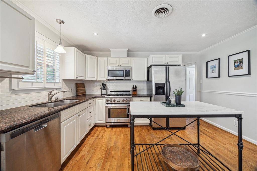Crisp white cabinetry pairs with granite counters, stainless appliances, and a marble-topped island to create a kitchen that’s both classic and functional. Subway tile backsplash and updated hardware add a polished touch.