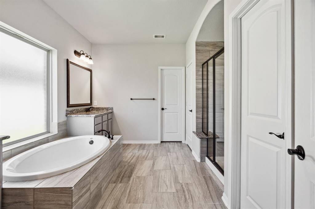 The primary bathroom features beautiful floors, dual sinks, walk-in shower, and separate tub.