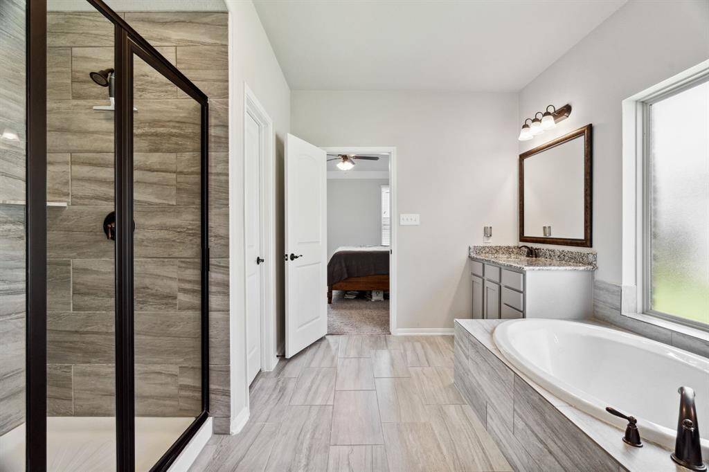 The spacious walk-in shower has tile surround and a glass door.