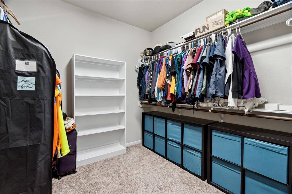 The primary walk-in closet features plush carpet and plenty of storage space.