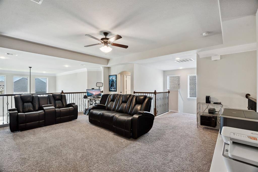 The upstairs game room features plush carpet, ceiling fan, and high ceilings.