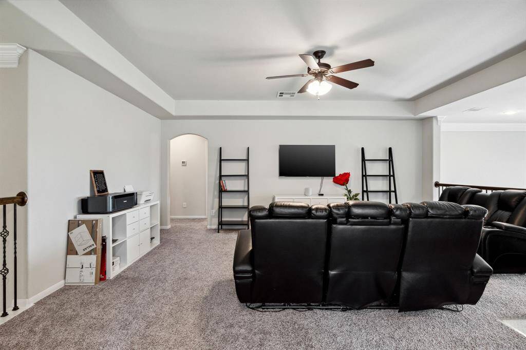 The upstairs game room features plush carpet, ceiling fan, and high ceilings.