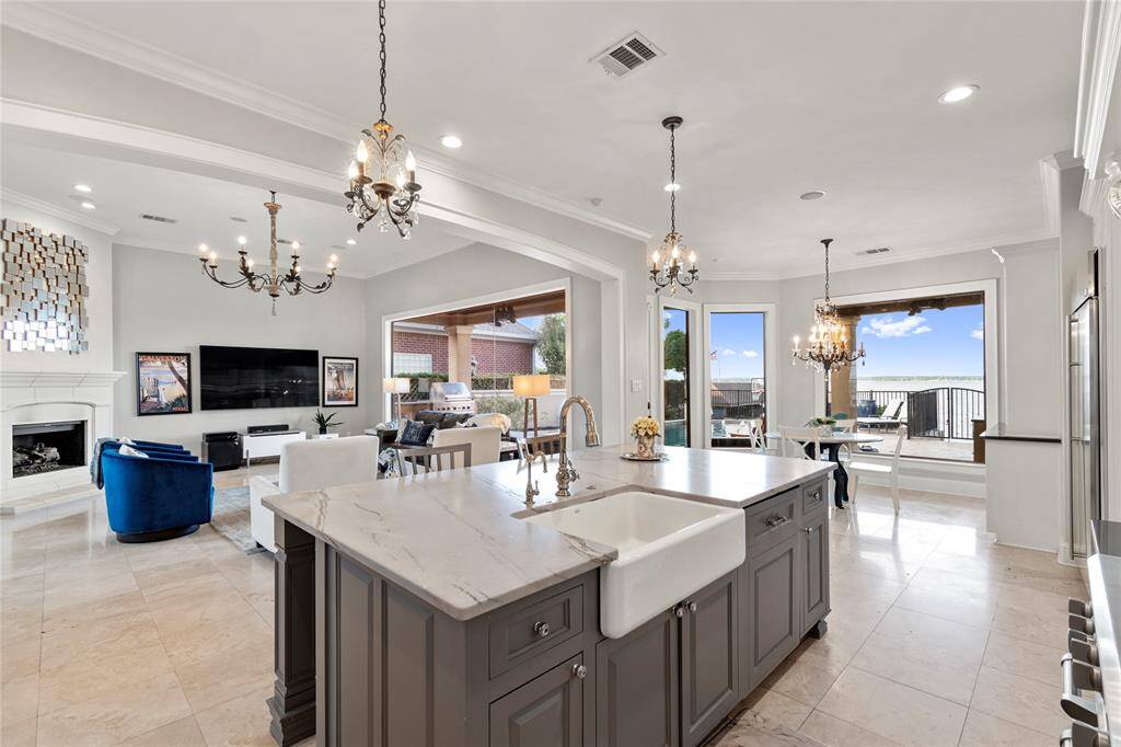 Gorgeous Kitchen Island. Beautiful faucet. Elegant pendants and layered lights throughout. The dishwasher has a cabinet cover, just to the right of the farmhouse sink.