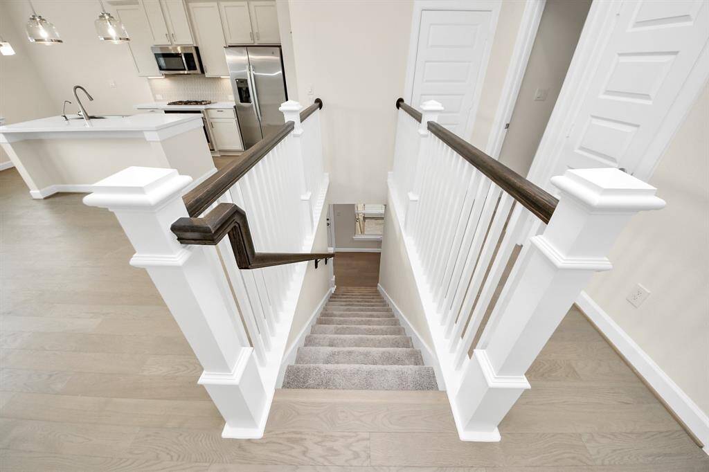 Let’s Step Into the Heart of the Home -Follow the crisp, carpeted staircase to the second floor and you’re welcomed into an open-concept living space that’s equal parts modern and inviting. From here, you’ll find sleek hardwood floors, a designer kitchen, and seamless flow—perfect for everything from solo nights to dinner parties. Benefits: Stylish wood and white stair railings; direct access to kitchen, dining, and living area; clean lines and elevated design details throughout.