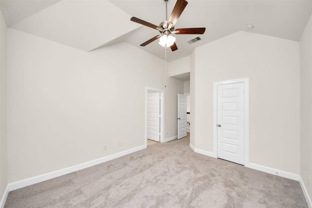 Peaceful Primary Suite with Vaulted Ceilings -This spacious primary retreat offers a calm, elevated feel with its soaring vaulted ceiling, neutral palette, and soft carpeting underfoot. Designed for rest and recharge, it features a ceiling fan, walk-in closet, and direct access to a private en-suite bath. Benefits: Generous layout for king-size comfort; ceiling fan for year-round climate control; steps from your private bathroom oasis.