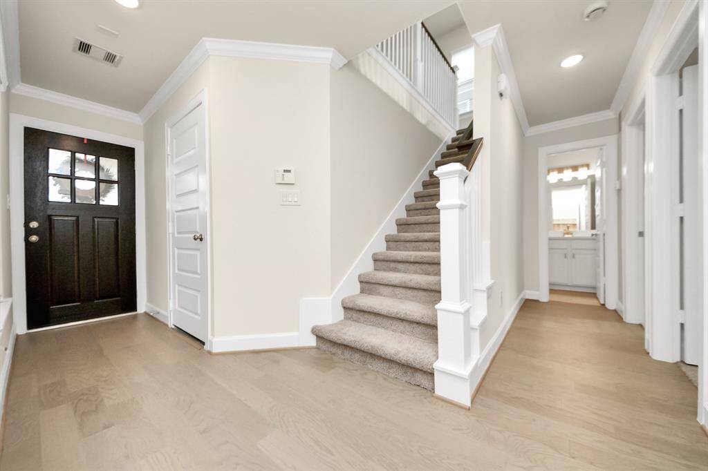 Function Meets Flow - Just inside the front door, this inviting entry opens to a thoughtfully designed first floor featuring two versatile bedrooms and a full-size bathroom—ideal for guests, friends, or a dedicated home office setup. Neutral tones, sleek wood flooring, and soft carpeted stairs offer comfort and style as you transition to the upper level. Benefits: Two bedrooms on the first level; full-size bath for convenience; perfect layout for flexibility and privacy and designed for how you live today.
