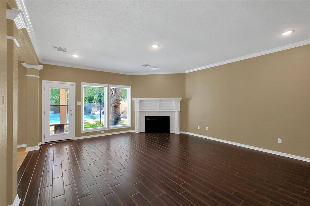 Large family room with gaslog fireplace overlooking sparkling pool.
