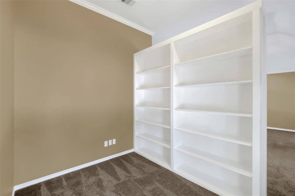 Custom bookshelf wall separates master bedroom and sitting/office area.