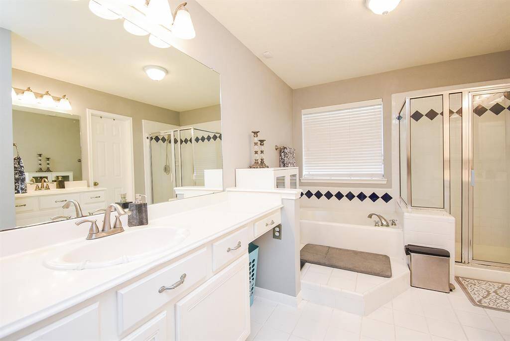 Tranquil, pale earth tones fill your primary ensuite bath, dotted with artistic tile. The sweeping white counter top hosts sink/vanity; wall wide mirror and delicate down lighting, above.