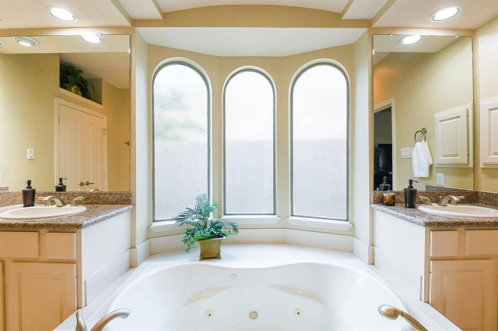 The jetted tub is surrounded by windows with privacy treatments.  Soak away your worries at the end of a hard day.