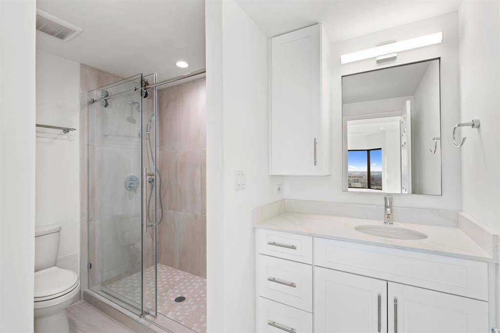 Primary bathroom with custom cabinetry, Quartz counters, designer fixtures and a seamless glass walk-in shower.