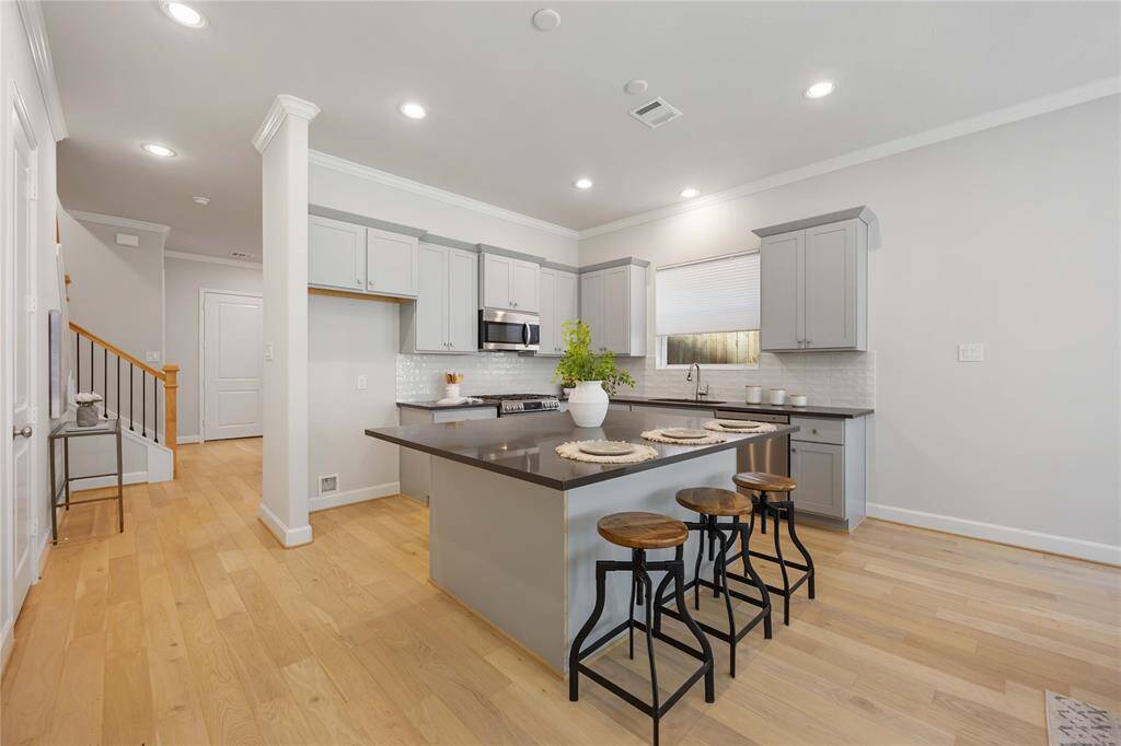 Another perspective highlights the kitchen’s expansive island—the true centerpiece of the home—offering a seamless flow into the adjacent dining room.