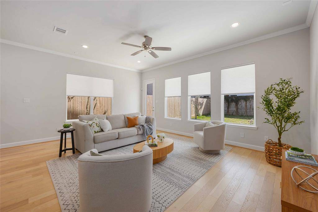 Floor-to-ceiling windows flood the open concept living room with natural light and provide peaceful views of the serene backyard.