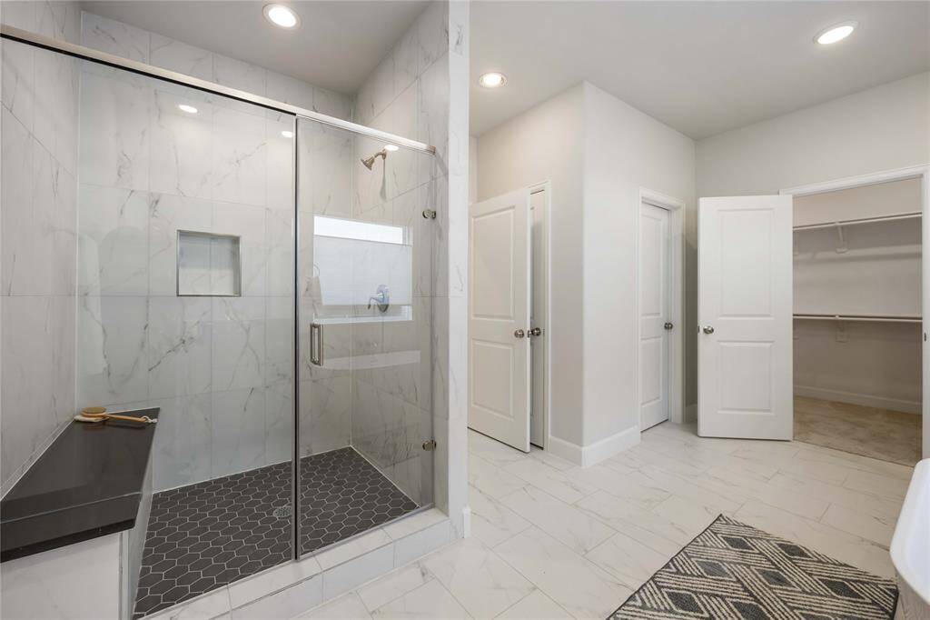 A large, step-in shower with bench seating and a separate water closet redefine luxury, making every morning a spa-like experience.