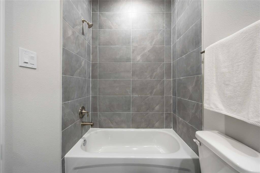The upgraded hall bathroom features sleek hexagonal floor tile and a classic tub/shower combo.