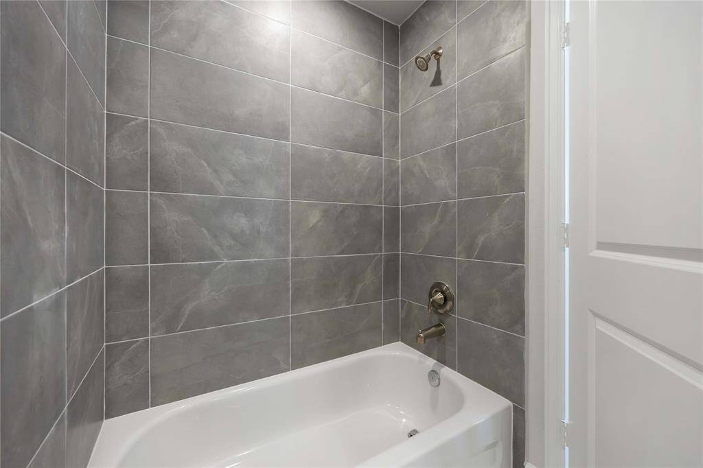 The ensuite third-floor bathroom features elegant tilework and a classic tub/shower combo