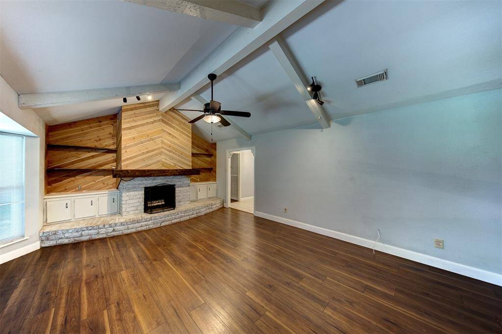 Living room with beautiful fireplace as the focal point with wood mantel and wood accent wall and shelving.