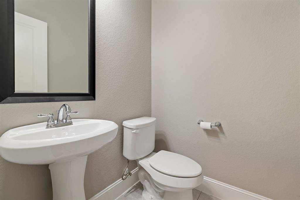 This convenient half bath is located just inside from the garage and mud room. The neutral color palette enhances a clean and simple look.