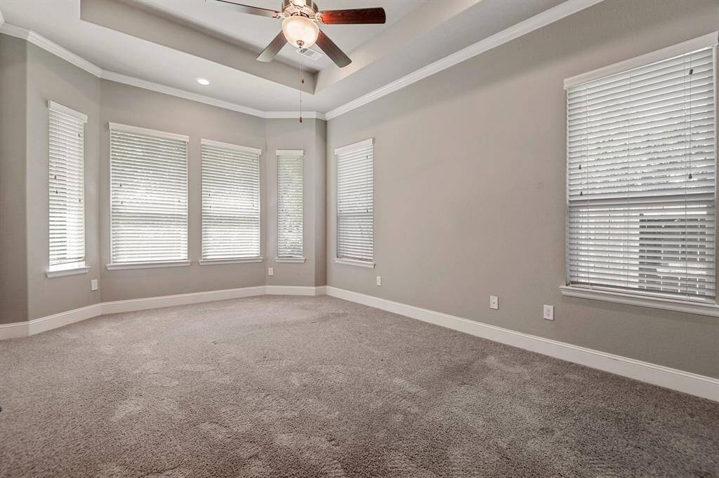 Spacious Primary Suite,  complete with carpet,with neutral walls, ample natural light from the extended bay windows, and a ceiling fan for comfort.