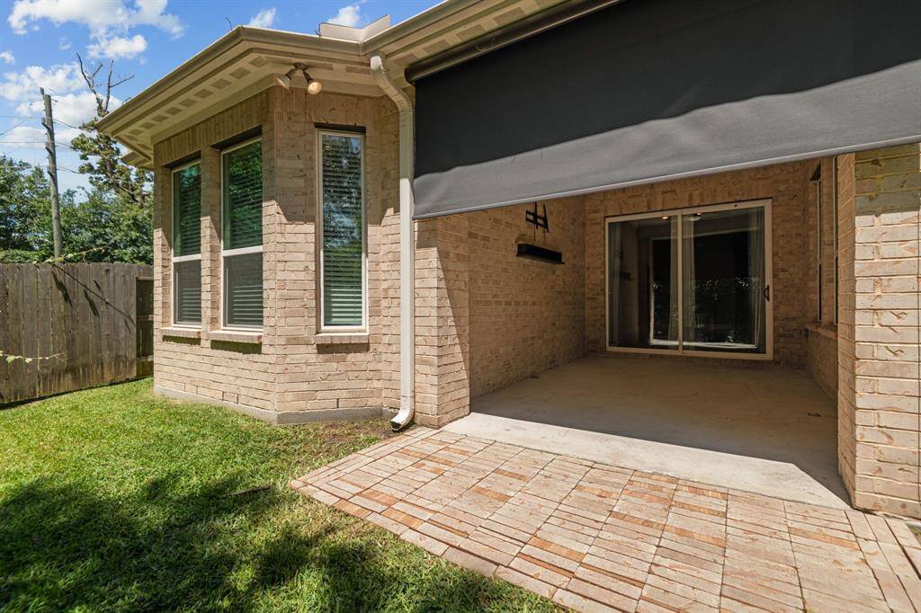 This photo showcases a cozy outdoor patio area with a brick exterior and sliding glass doors, ideal for relaxing or entertaining. There is also a retractable screen for added shade or privacy