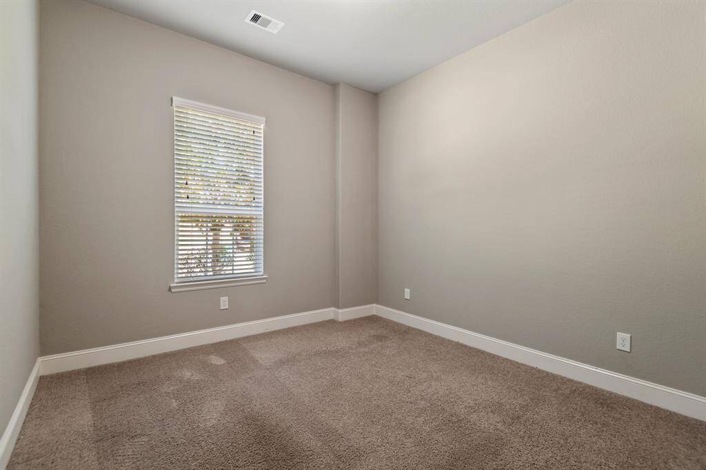 This photo shows the Secondary Bedroom 1 complete with neutral walls, carpeted flooring and a ceiling fan