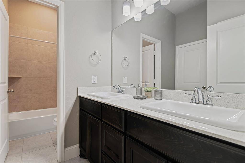Secondary bathroom featuring a double sink vanity with dark wood cabinets and a white countertop. Complete with Tub/Shower combo.