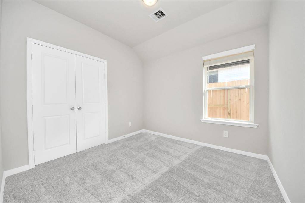 Secondary bedroom features plush carpeting, large windows that let in plenty of natural light, bright paint, and spacious closets.